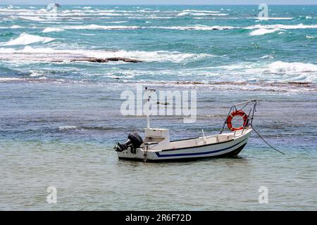 small beached Fishing boat. Photographed in Jaffa, Israel. Bat Yam in the Background Stock Photo