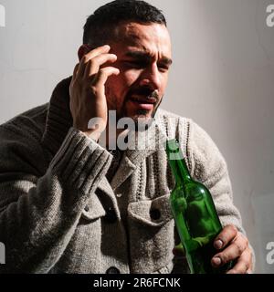 Alcoholic man with bottles wine cry. Depressed crying man. Drunk men drinking alcohol feeling lonely and desperate in emotional stress. Stock Photo