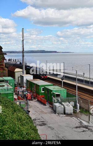 A steam train passing through Dawlish station during building works to construct a new platform and footbridge in 2023. Stock Photo