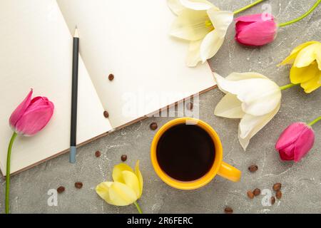 Notebook with cup of coffee and tulips on grey background. Top view Stock Photo