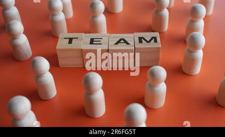 Wooden dolls and text TEAM. Colleague, teamwork, support, cooperation concept. Stock Photo