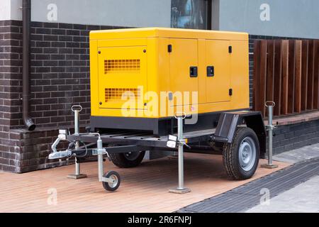 Mobile diesel charge generator for emergency electric power standing outside of modern building. Stock Photo