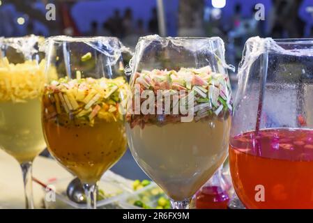 tropical drinks juice and tea with guava, citrus fruits in big glasses in vietnamese street market at night Stock Photo
