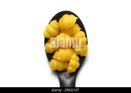 Raw pasta gnocchetti on wooden spoon on White background. Top view of Italian cuisine ingredient. Stock Photo