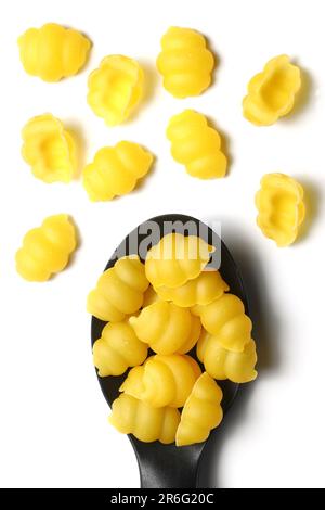 Raw pasta gnocchetti on wooden spoon on White background. Top view of Italian cuisine ingredient. Stock Photo