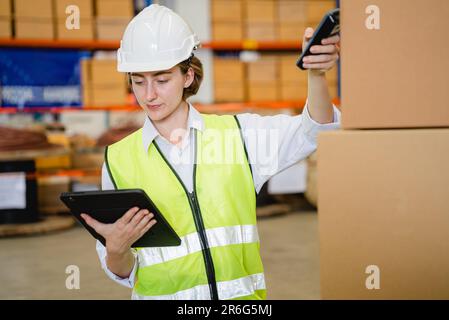 Engineer with safety vest using tablet checking goods on shelves Stock Photo