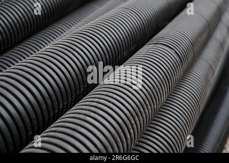 Black building pipes, selective focus, coated corrugated pipes for road and electrical network repair, top view. Reconstruction and improvement of the Stock Photo