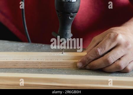 Close up of hands of a carpenter using electric mini drill. Unrecognizable man practicing a hobby Stock Photo