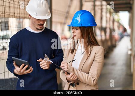 Mand and woman architects using touchpad write on report at street Stock Photo