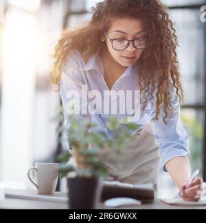 A young woman makes a report in the office. Woman writing notes for educational project in business Stock Photo