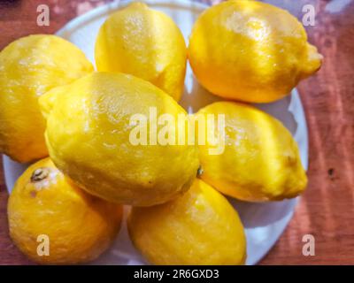 Juicy ripe flying yellow lemons, green leaves on light gray background. Creative food concept. Tropical organic fruit citrus vitamin C. Stock Photo