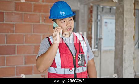 builder talking on smartphone at construction site Stock Photo