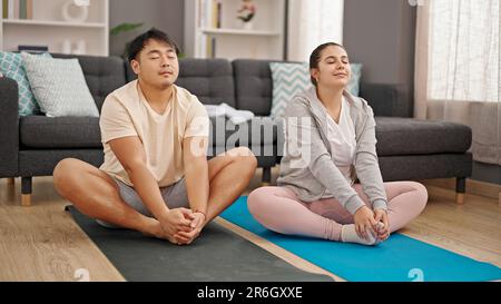 Man and woman couple sitting on floor doing yoga exercise at home Stock Photo