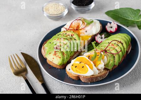 Healthy breakfast - sandwiches with avocado, egg and sesame on round plate Stock Photo