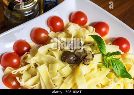 Tagliatelle noodle with Truffle mushroom slices and cherry tomotoes and basil leaf Stock Photo
