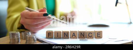 Woman pointing on word finance collected of wooden blocks in row Stock Photo