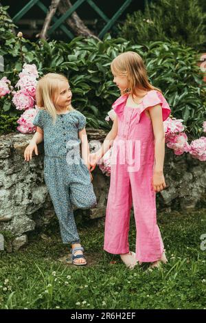 Outdoor portrait of two sweet little girls, kids playing together in summer garden Stock Photo