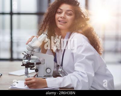 Attractive female scientist looking through a microscope Stock Photo