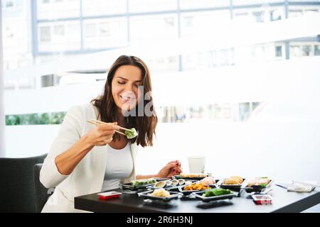 Young woman eating business lunch in sushi restaurant Stock Photo