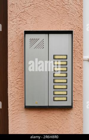 Modern intercom hanging on beige wall outdoors Stock Photo