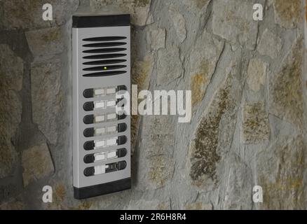 Modern intercom on concrete wall with stone fragments, space for text. Security system Stock Photo