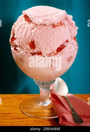 1980s GLASS DESSERT CUP FULL OF STRAWBERRY ICE CREAM SPOON ON PINK NAPKIN - kf22429 FRT001 HARS OLD FASHIONED Stock Photo