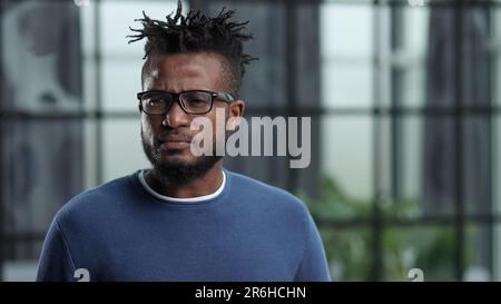 Close-up of a young african american business man entrepreneur wearing eyeglasses contemplating in office Stock Photo