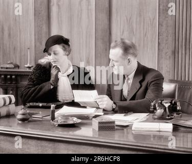 1930s SAD FASHIONABLE WOMAN SEATED BESIDE HER ATTORNEY REVIEWING DOCUMENTS WILLS DIVORCE DECREE LEGAL ADVICE - o1336 HAR001 HARS STYLE FEAR COMMUNICATION INFORMATION WORRY MYSTERY FASHIONABLE LIFESTYLE FEMALES MOODY SEATED COPY SPACE HALF-LENGTH LADIES PERSONS WILL MALES TROUBLED B&W CONCERNED SADNESS SUIT AND TIE DOCUMENTS DISCOVERY STYLES DEATH JUDICIAL LAWYERS JUDGMENT ATTORNEYS MOOD OCCUPATIONS TESTAMENT REVIEWING CONCEPTUAL GLUM BESIDE STYLISH LAST WILL ATTORNEY INHERITANCE MISERABLE WILLS BLACK AND WHITE CAUCASIAN ETHNICITY HAR001 OLD FASHIONED Stock Photo