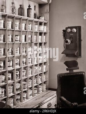 1910s ANTIQUE BARBER SHOP RACK OF INDIVIDUAL PERSONAL SHAVING SOAP MUGS AND WOODEN WALL PHONE RICHMONDTOWN STATEN ISLAND NY USA - q57233 CPC001 HARS STRATEGY CUSTOMER SERVICE NYC OCCUPATIONS PHONES NEW YORK TELEPHONES CITIES MUGS NEW YORK CITY BARBER'S CHAIR BOROUGH BLACK AND WHITE INDIVIDUAL OLD FASHIONED STATEN ISLAND WALL PHONE Stock Photo