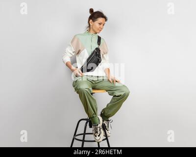 Full Length Body Portrait of a Woman Wearing Crossbody a Black Leather Belt Bag over Grey Background. Handmade Leather Accessories Goods Stock Photo