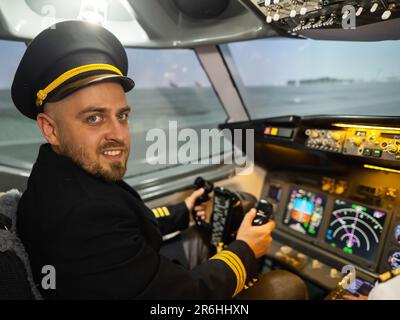 Caucasian bearded man smiling while sitting in a flight simulator. Pilot in the cockpit. Stock Photo