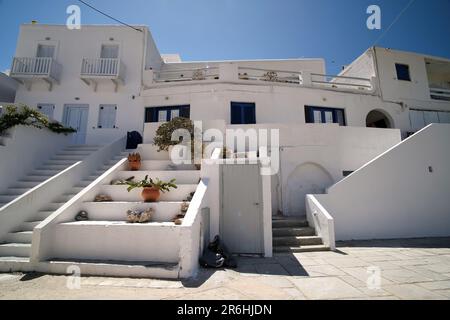 Ios, Greece - May 16, 2021 : A  whitewashed hotel that rents rooms, with the typical Cycladic architecture,  in front of the  Mylopotas Ios Greece Stock Photo