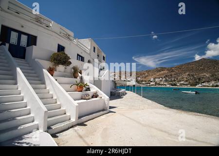 Ios, Greece - May 16, 2021 : A  whitewashed hotel that rents rooms, with the typical Cycladic architecture,  in front of the  Mylopotas Ios Greece Stock Photo