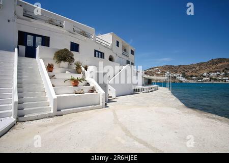 Ios, Greece - May 16, 2021 : A  whitewashed hotel that rents rooms, with the typical Cycladic architecture,  in front of the  Mylopotas Ios Greece Stock Photo