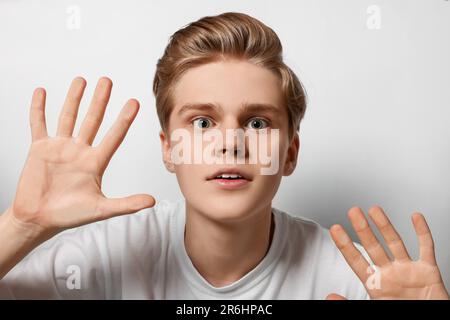 Excited teenage boy stuck to transparent screen Stock Photo