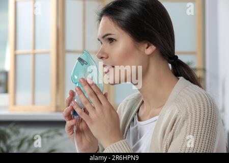 Sick young woman using nebulizer at home Stock Photo