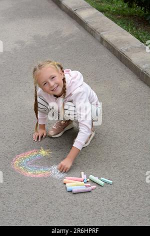 Little child drawing rainbow with chalk on asphalt Stock Photo - Alamy
