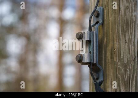 Wire connector for ground wire on a wooden electric pole outdoors, close up. Stock Photo