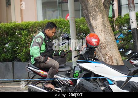 People wait for their ride-hailing transportation as workers load boxes ...