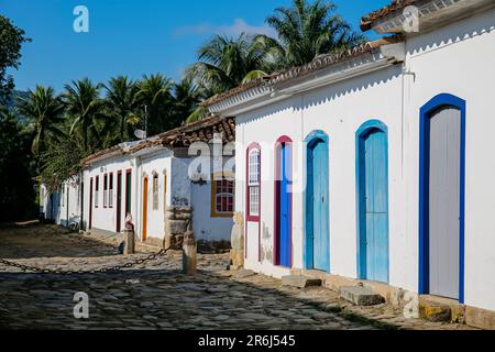 Typical house facades in sunshine with colorful doors and windows, in the background palm trees, historic town Paraty, Brazil Stock Photo