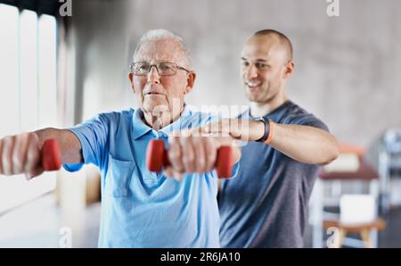 Physiotherapist, senior man and rehabilitation with dumbbells, fitness and exercise for recovery, help and training. Mature male person, client or Stock Photo