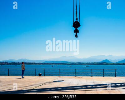 Silhouettes of people walking along a quay in the port of Santander. Stock Photo
