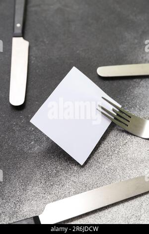 Blank card and stainless steel cutlery on green background Stock Photo ...