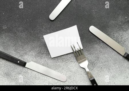 Blank card and stainless steel cutlery on green background Stock Photo ...