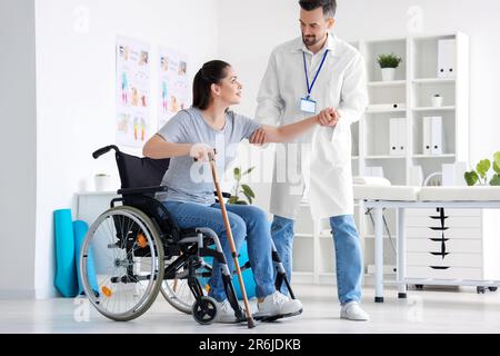 Male physiotherapist helping young woman to stand up in rehabilitation center Stock Photo