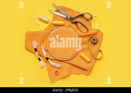 Embroidery hoop with canvas, mouline threads and measuring tape on yellow background Stock Photo