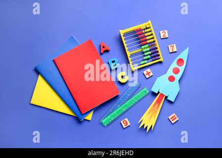 Paper rocket with abacus, wooden letters and different stationery on dark blue background Stock Photo