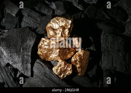 Golden nuggets on black charcoal Stock Photo