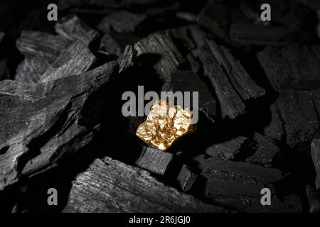 Golden nugget on black charcoal Stock Photo