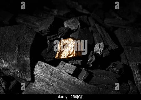 Golden nugget on black charcoal Stock Photo